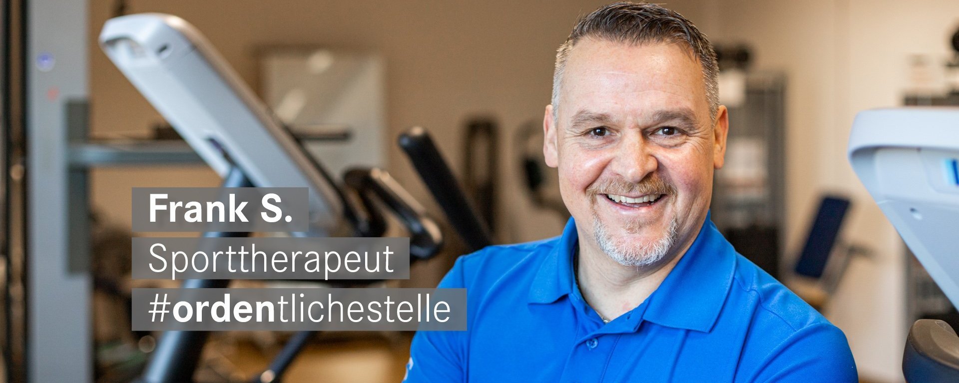 Sporttherapeut mit wenig Bart laechelt freundlich in die Kamera