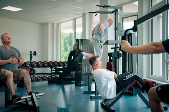 Drei Männer machen Sport in einem Fitnessraum.