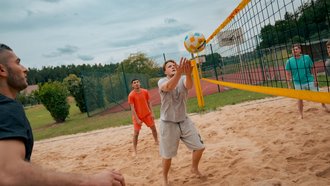 Fünf Männer spielen Volleyball.